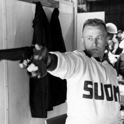 Mustavalkokuva vuoden 1964 Tokion olympialaisista. Kuvassa Väinö Markkanen. Hän poseeraa vapaapistoolinsa kanssa.