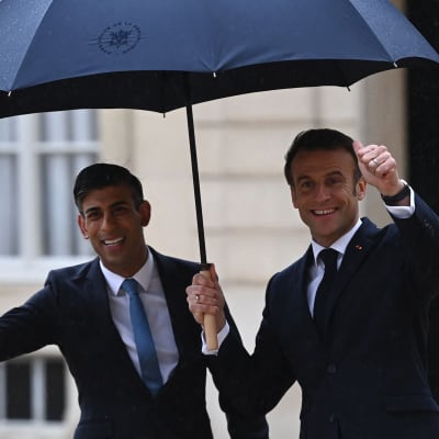 Frankrikes president Emmanuel Macron och Storbritanniens premiärminister Rishi Sunak under ett paraply.