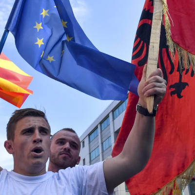 Två män viftar med Nordmakedoniens, Albaniens och EU:s flagga.
