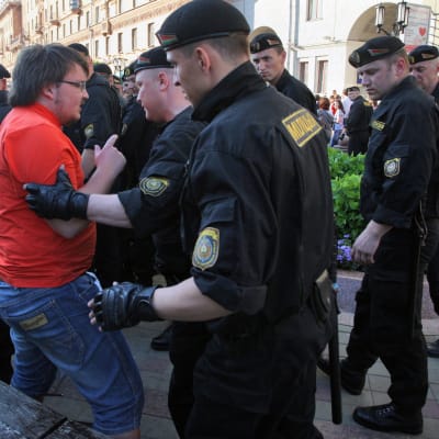 Vitrysk polis håller i en demonstrant som i sin tur försöker förklara något.