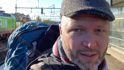 Matkailun tutkija Mikko Manka junamatkalla Ruotsissa. Seisoo aseman laiturilla reppu selässään.