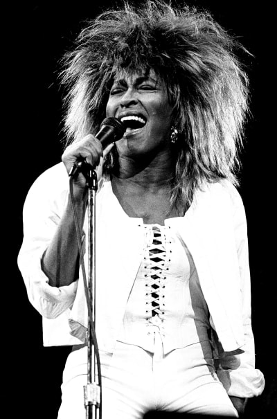 Tina Turner på scen i ljusa byxo, korsett och jacka.