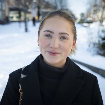 Nuori nainen kaupungilla lumisessa maisemassa.
