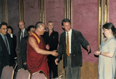 En grupp människor välkomnar Dalai Lama i en matsal.