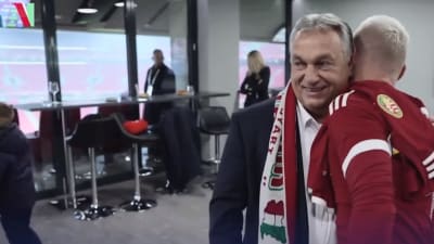 Viktor Orbán klädd i halsduk kramar en fotbollsspelare.