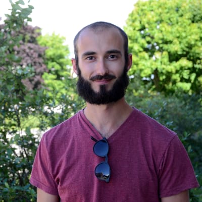 Anders Englund utomhus framför en grön buske.