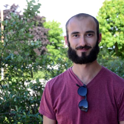 Anders Englund utomhus framför en grön buske.