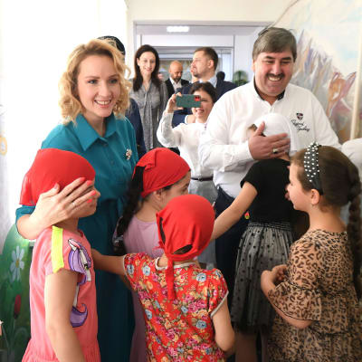 Maria Lvova-Belova hymyilee ja syleilee lapsia.
