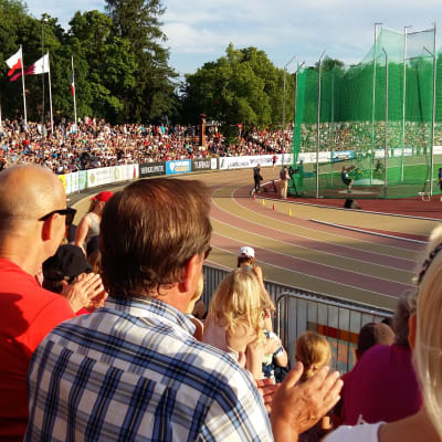 Fullt med publik följer med friidrottstävlingar i sommarvärmen på Paavo Nurmi stadion i Åbo. Släggkastning på gång.