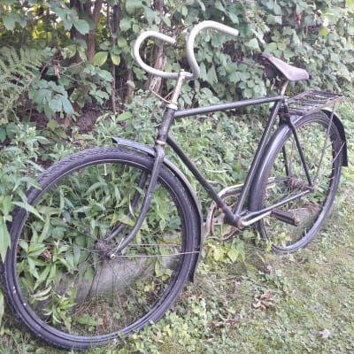 En gammal cykel av modellen Felix Special står vid en häck.