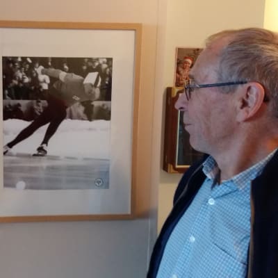 Hastighetsåkaren Olavi Hjellman tittar på tavlor av sig själv från en skridskotävling och av diplomet från vinter-OS 1968 i Grenoble.