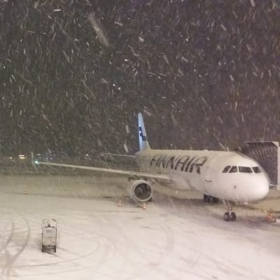Ett Finnairplan väntar i snöyra på att börja ta emot passagerare.