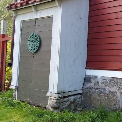 Ett litet förråd byggt mot en husfasad.