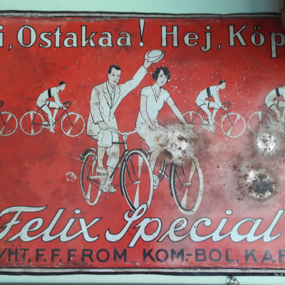 En röd gammal skylt i metall som visar ett par som cyklar. På skylten står det: Hej! Köp Felix Special.