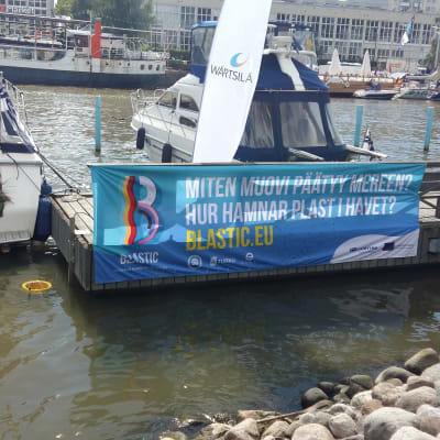 En havssoptunna finns i Åbo gästhamn, med en stor banderoll invid: Hur hamnar plast i vattnet?