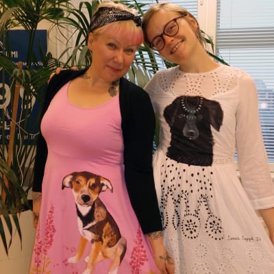 Katukoirien auttajat Riikka Hietala ja kuvataiteilija Sanni Seppä esittelevät Sepän kuvittamia mekkoja.