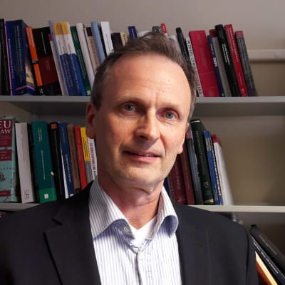 Professor Kimmo Nuotio står framför en bokhylla.