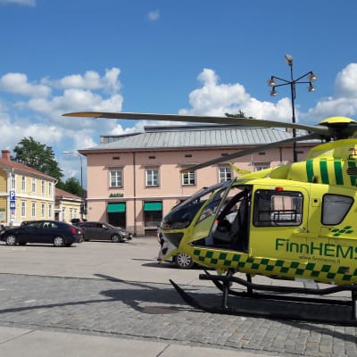 En gul räddningshelikopter står på ett torg.