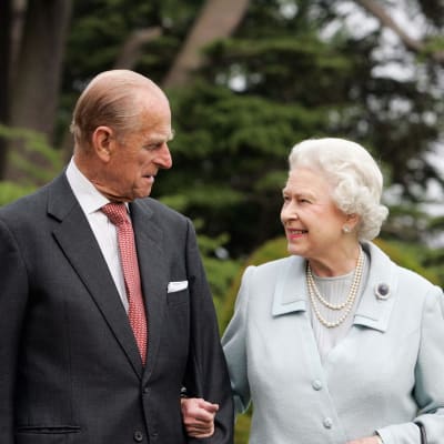 Prins Philip, hertig av Edinburgh, och drottning Elizabeth II av Storbritannien ser på varandra leende medan de står arm i arm.