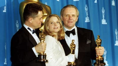 Jonathan Demme, Jodie Foster och Anthony Hopkins håller i var sin Oscarsstatyett.