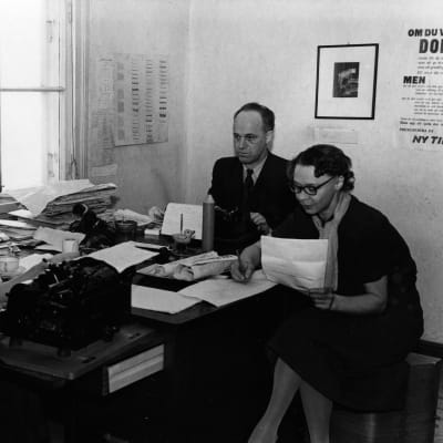 Tre personer, två kvinnor och en man, runt ett bord på en redaktion. Svartvit bild.