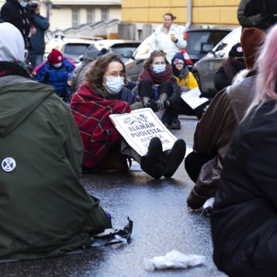 Elokapina mielenosoittajat istuvat kadulla.