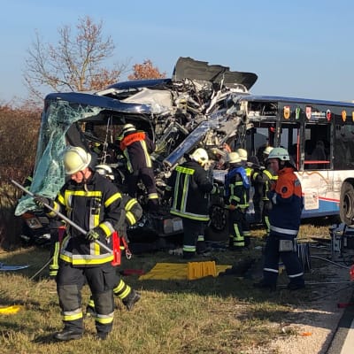 Två skolbussar som har krockat med varandra, räddningspersonal går omkring runt bussarna.