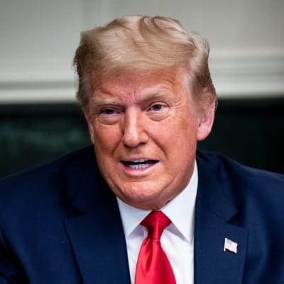 Bild på Donald Trump iförd i röd slips som viftar med händerna.