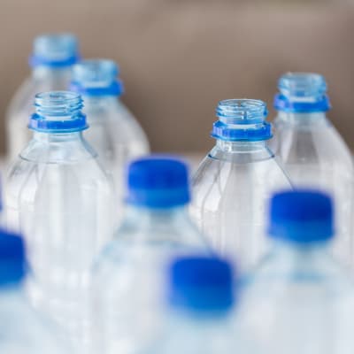 Vattenflaskor i plast med blå skruvkork.