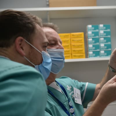 Två personer granskar ett coronavaccin.
