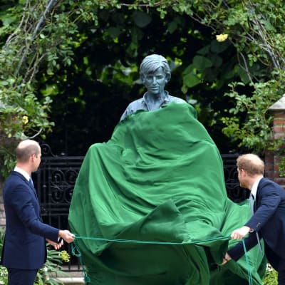 Sönerna Harry och William drar av ett grönt skynke som täckt sttatyn