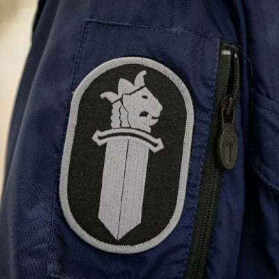 Poliisin virkamerkki työhaalarin hihassa
