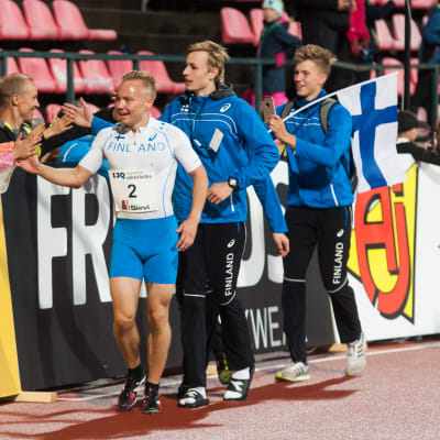 Tre friidrottare med Joonas Rinne i spetsen tackar publiken.