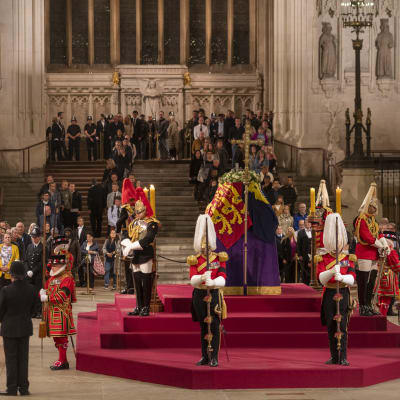 Människor defilerar förbi drottning Elizabeths kista i Westminster Hall. Kistan vaktas av soldater i paraduniformer med plymer på hjälmen.