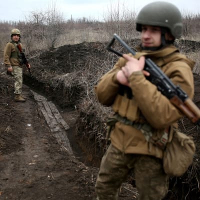 Två ukrainska soldater patrullerar längs en lerig löpgrav