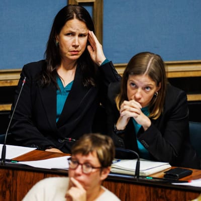 Veronika Honkasalo och Li Andersson sitter i riksdagens plenisal.