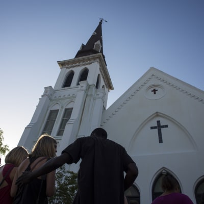 Folk tröstar varandra utanför den kyrka där skjutningen i Charleston ägde rum