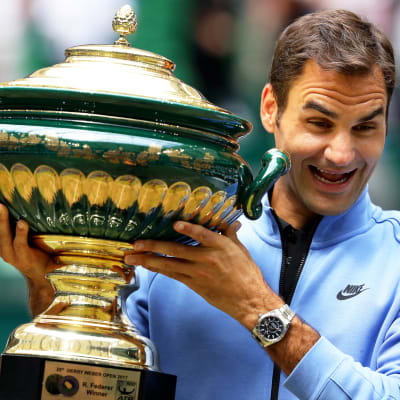 Roger Federer ser lycklig ut med en pokal i handen.