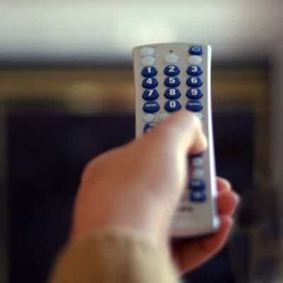 Hand håller upp tv-fjärrkontroll