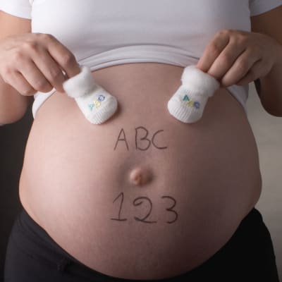 En gravid mage med bokstäverna ABC och siffrorna 123 skrivna på magen. 