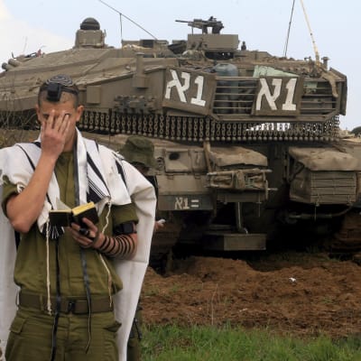 En israelisk soldat ber nära Gazaremsan