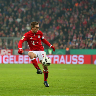 Rödklädde fotbollsspelaren Philipp Lahm håller fotbollen i luften med högerfoten.