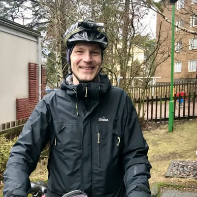 Anders Munck med cykelhjälm och cykel framför dagisgård.