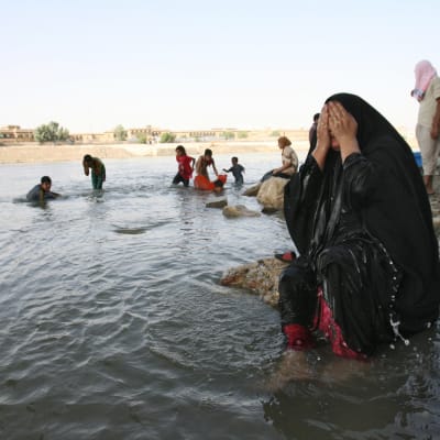 Kvinna svalkar sig med vatten vid floden Tigris i Bagdad