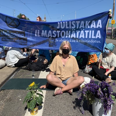 Aurora Blomberg protesterar för Elokapina framför en skylt. 