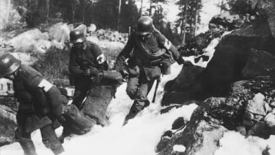 Tyska soldater bär en skadad rödgardist bort från klipporna i Fredriksberg(Böle) i Helsingfors år 1918.