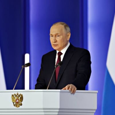 Rysslands president står vid ett poduim och håller sitt årliga tal 21. februari 2023. 