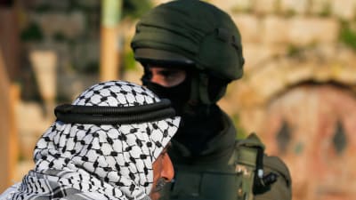 Palestinier och israelisk soldat i byn Salem öster om Nablus på Västbanken under en israelisk räd mot palestinier 18.3.2019