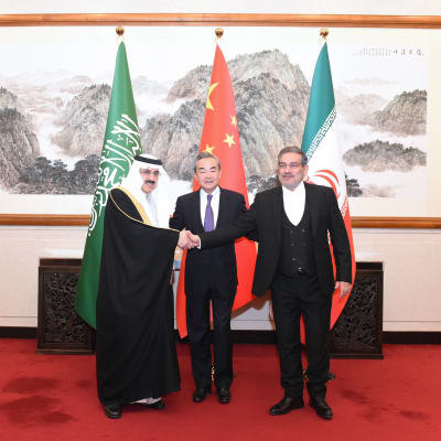 Saudiarabiens nationella säkerhetsrådgivare Musaid Al Abain skakar hand med Irans högsta säkerhetschef, general Ali Shamkhani, med Kinas utrikesminister Wang Yi i mitten. 