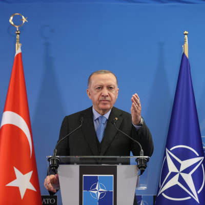 Turkin presidentti Recep Tayyip Erdoğan puhuu Naton päämajassa Brysselissä maaliskuun huippukokouksen jälkeen takanaan Turkin ja Naton liput.
